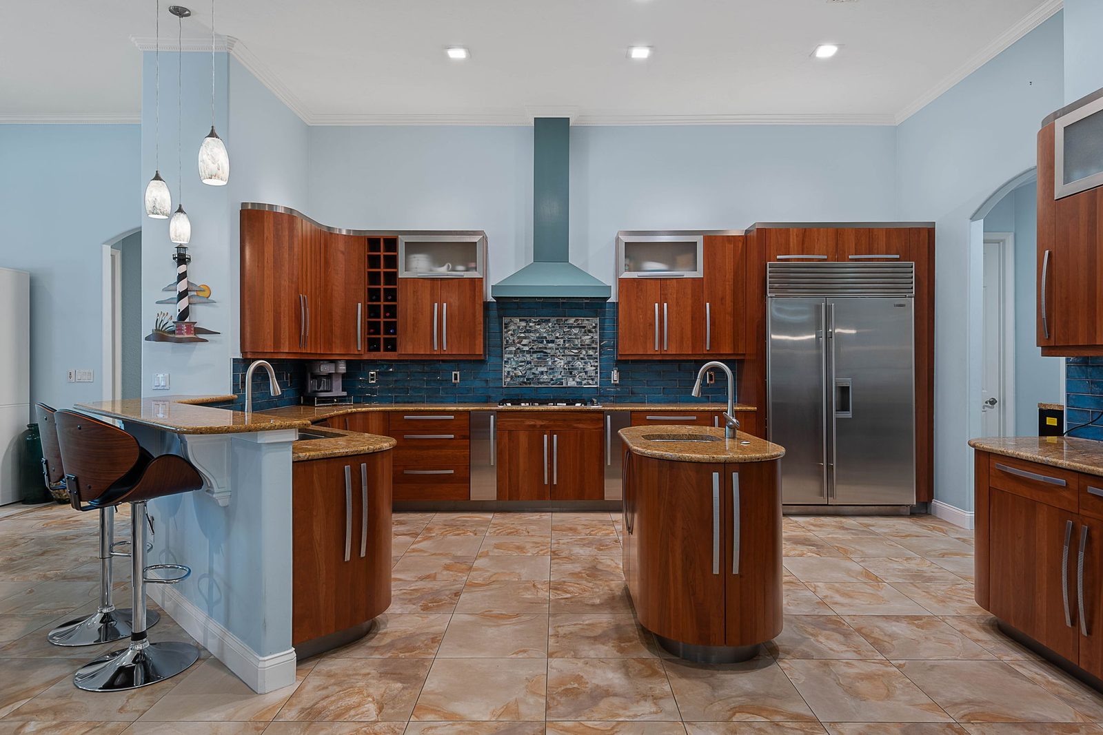 Chef's kitchen with cherry cabinetry, granite counters, Sub-Zero refrigerator, and blue-glass tile backsplash